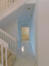 Two-story foyer with a bifurcated staircase featuring white railings, carpeted treads, and tiled flooring