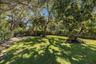Expansive lawn featuring mature trees and established landscaping