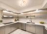Contemporary kitchen featuring stainless steel cabinetry, white countertops, integrated cooktop, stainless steel range hood, and a modern ceiling ligh