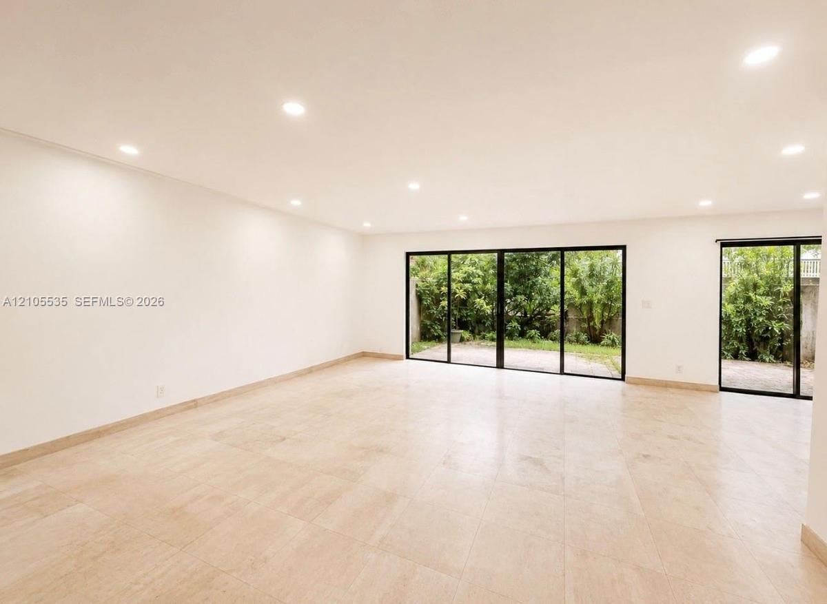 Spacious room featuring light-toned tiled flooring, recessed lighting, and expansive glass sliding doors