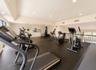 Spacious fitness area featuring rubber flooring, recessed lighting, and various exercise equipment