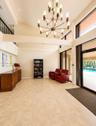 Vaulted ceilings with exposed beams, large format tile flooring, a multi-tier chandelier, and expansive windows