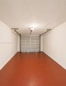 Garage with a sealed concrete floor, automatic garage door opener, and a ceiling-mounted light fixture