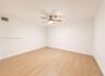Wood-finish flooring, white paneling, ceiling fan with integrated lighting, and ceiling-mounted air vent