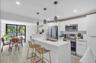Contemporary kitchen featuring white cabinetry, stainless steel appliances, and a central island with an integrated sink