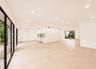 Spacious interior with neutral tile flooring, recessed lighting, expansive glass doors, and built-in shelving units
