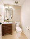 Modern vanity with slatted wood-finish cabinetry, white integrated sink, and brass-finish fixtures