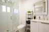 Glass-enclosed shower with white tiled walls and a hex-tile floor