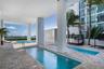 Covered outdoor area featuring multiple pools, paved decking, and palm trees
