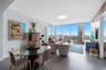 Floor-to-ceiling windows, light gray tile flooring, open-concept living space, built-in ceiling light fixture, and city skyline