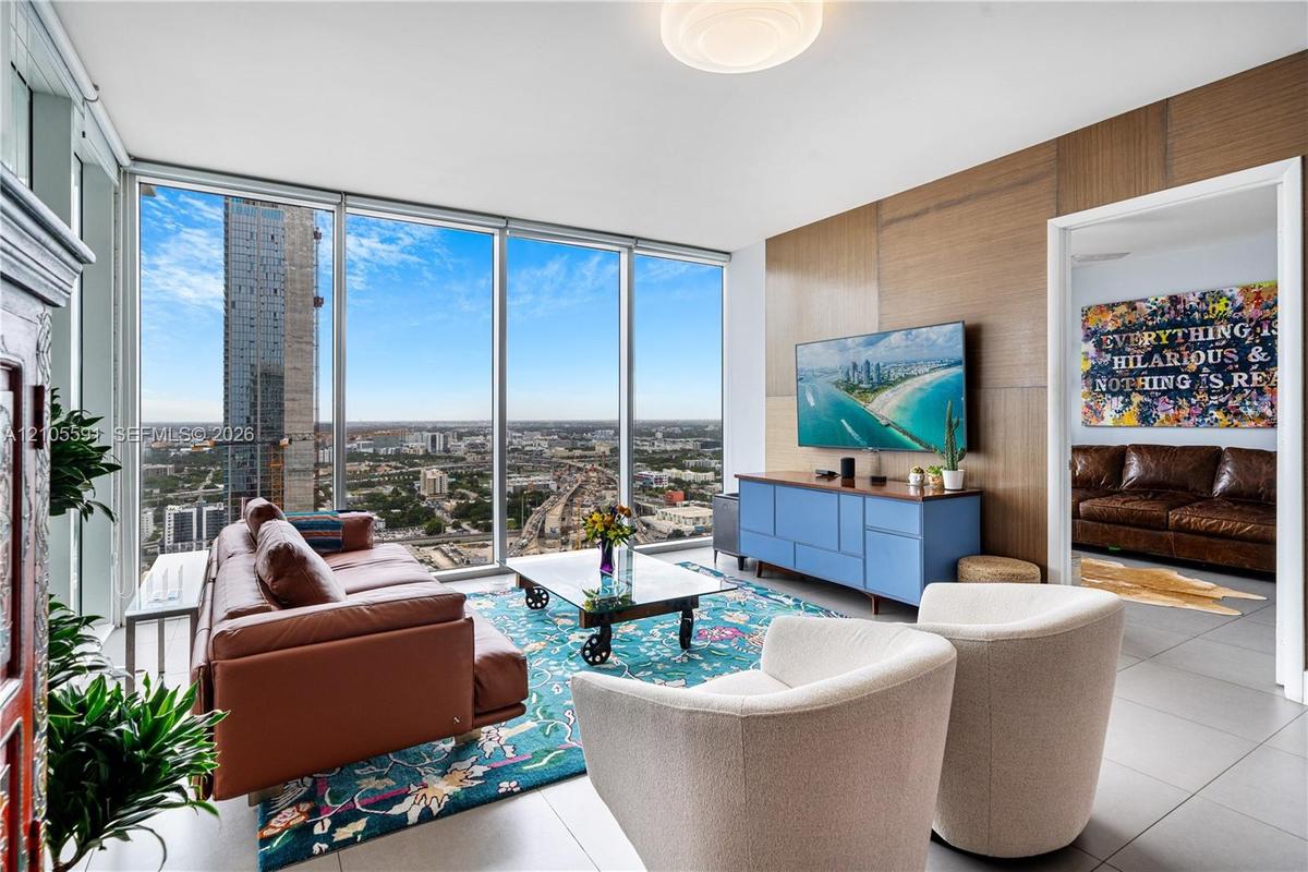 Floor-to-ceiling windows, wood-finish accent wall, ceiling-mounted lighting fixture, and light tile flooring