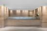 Wood-paneled reception area featuring a frosted glass counter, recessed ceiling lighting, and overhead accent lighting