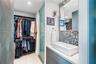 Built-in closet system, tile flooring, glass shower enclosure, vanity with basin sink, and patterned wall tile