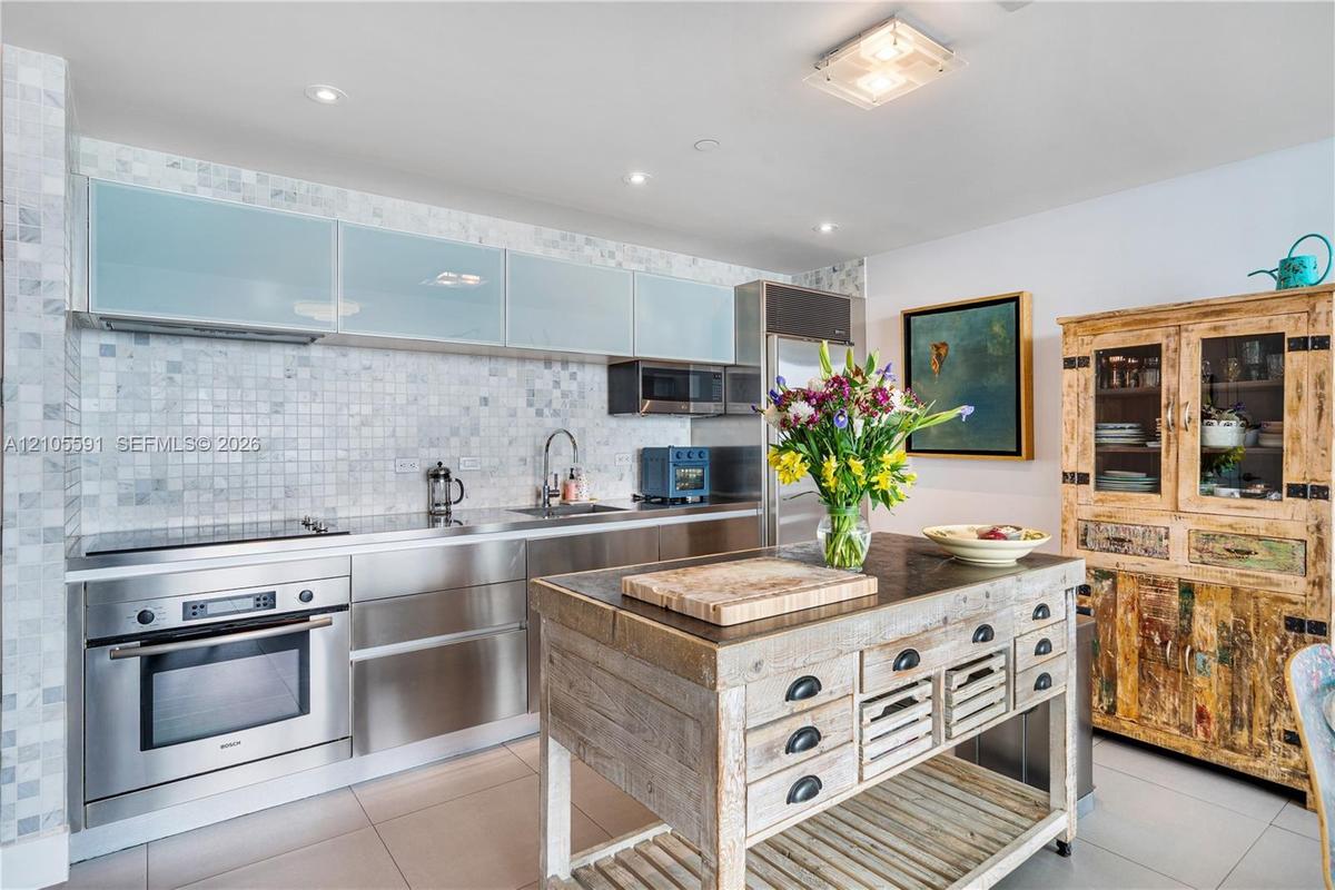Stainless steel appliances, mosaic tile backsplash, recessed lighting, and a unique wood-finish kitchen island
