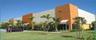 Commercial building with a tan and orange exterior, multiple entryways, and mature landscaping