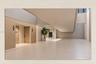 Spacious interior with light-toned tile flooring, light wood-finish wall panels, and high ceilings