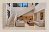 Two-story open concept living area featuring a grand staircase, built-in shelving with integrated lighting, and expansive windows