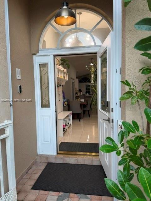 Entryway featuring an arched transom window, a white paneled door with decorative glass inserts, and a bronze-finish pendant light fixture