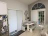Arched transom window, sliding glass patio door, tiled flooring, white cabinetry, and recessed lighting