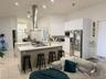 Kitchen featuring white cabinetry, stainless steel appliances, a center island with seating, and recessed lighting