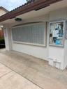 Mailbox station featuring multiple lockable compartments, exterior lighting, a tiled roof overhang, and a community bulletin board