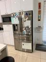 Stainless steel refrigerator, built-in microwave, white cabinetry, recessed lighting, and tile flooring