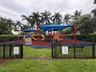 Playground area featuring multiple slides, climbing structures, and a seesaw, all shaded by blue canopies