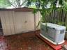 Storage shed with a pitched roof and a permanently installed generator unit on a solid base