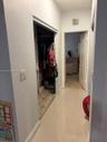 Hallway with light tile flooring, leading to an open doorway with a full bathroom beyond