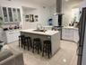 Contemporary kitchen featuring white cabinetry, a central island with an integrated sink, stainless steel appliances, and tile flooring