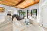 Vaulted wood-paneled ceiling with exposed beams, full-height wall mirror, dark wood dresser, and exterior sliding glass doors