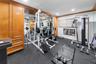 Custom built-in cabinetry, full-wall mirror, window with horizontal blinds, ceiling-mounted recessed lighting, and rubberized flooring