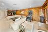 Wood-paneled wall, recessed lighting, and a built-in wet bar with mirrored backsplash