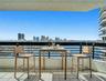 Expansive balcony with tiled flooring, black metal railing, and high-rise city scenery