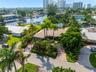 Waterfront property featuring a private dock, lush tropical landscaping, mature palm trees, a circular driveway, and a tiled roof