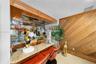Built-in bar with wood cabinetry, mirrored backsplash, and stone countertop