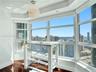 Bay window with expansive city and ocean scenery, complemented by wood-finish flooring and a spherical ceiling fixture