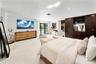 Recessed lighting, light-toned carpeting, built-in dark wood cabinetry, glass sliding doors, and white walls