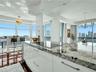Sleek kitchen island with a built-in cooktop and stone countertop, open concept living area, recessed lighting, expansive floor-to-ceiling windows, an