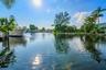 Waterfront property featuring a private boat dock, lush tropical landscaping, and canal access