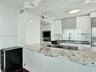 Kitchen featuring a curved stone countertop, built-in cooktop, white upper cabinetry, and a stainless steel oven