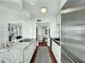 Modern kitchen featuring high-gloss white cabinetry, integrated stainless steel appliances, and wood-finish flooring