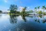 Waterfront property with private boat dockage, mature palm trees, and manicured lawn