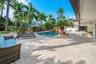 Expansive paved patio surrounding an irregular shaped pool with rock features and mature tropical landscaping