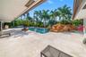 Expansive outdoor living area featuring a large swimming pool, rock water feature, and extensive patio paving