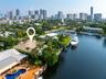 Waterfront property featuring a private boat dock, lush landscaping with mature palm trees, a swimming pool, and a tiled roof, with a city skyline in 