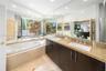 Dual vanity with stone countertops and undermount sinks, full-height wall mirrors, built-in soaking tub, and large window