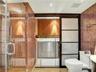 Full-height mosaic tile, glass-enclosed shower, built-in cabinetry, modern sliding door, and stackable laundry appliances