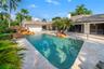 Rectangular swimming pool with rock waterfall feature, integrated steps, and surrounding patio