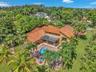 Mediterranean-style residence with a red tile roof, private swimming pool, integrated spa, covered patio, and lush tropical landscaping
